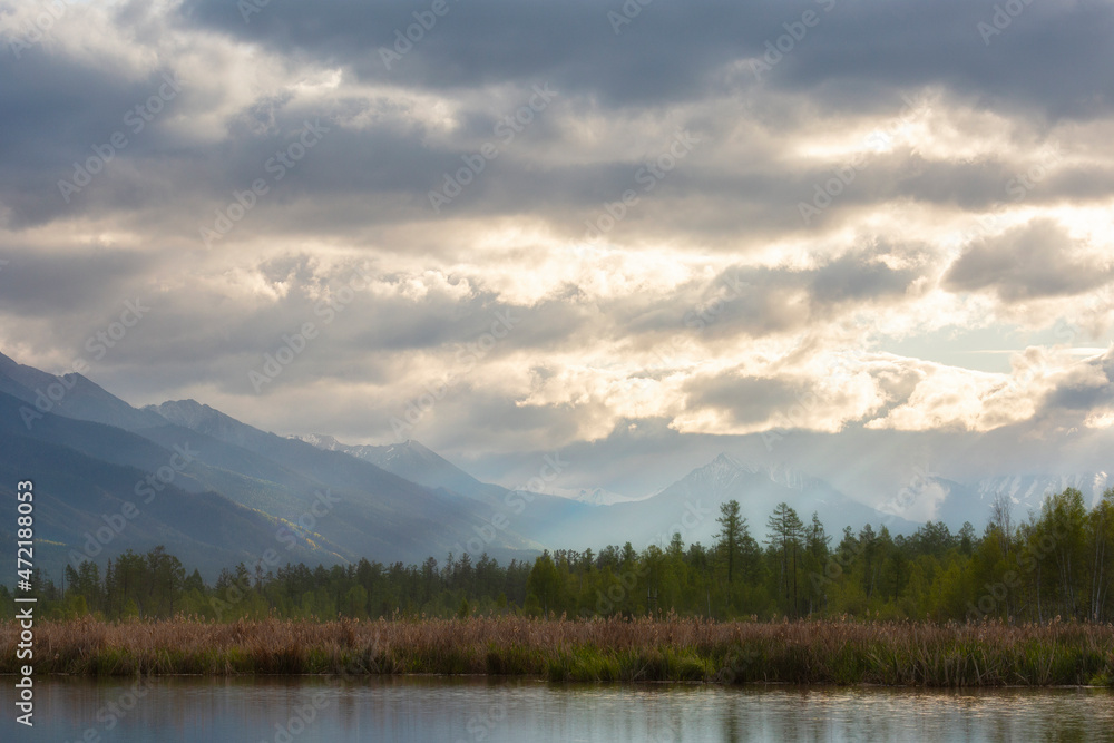 Landscape with mountains reflecting in the water on cloudy summer day. Buryatia, Tunkinskaya valley