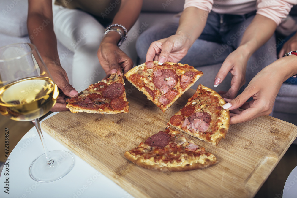 Hands taking pizza slices from wooden table, close up view