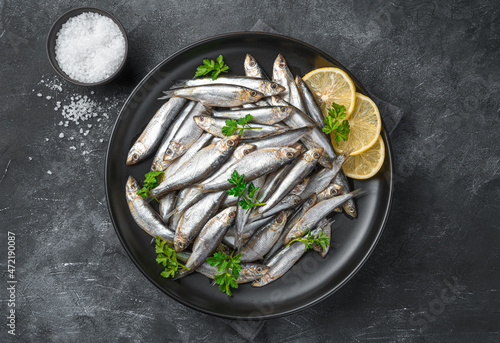 Fototapeta Naklejka Na Ścianę i Meble -  Sardines with lemon, salt and parsley close-up on a dark background. Sea fish. Top view.