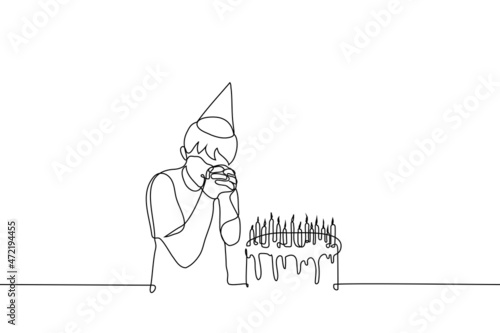 birthday boy in cap makes wish over cake with burning candles - one line drawing vector. birthday party concept, cherished wish
