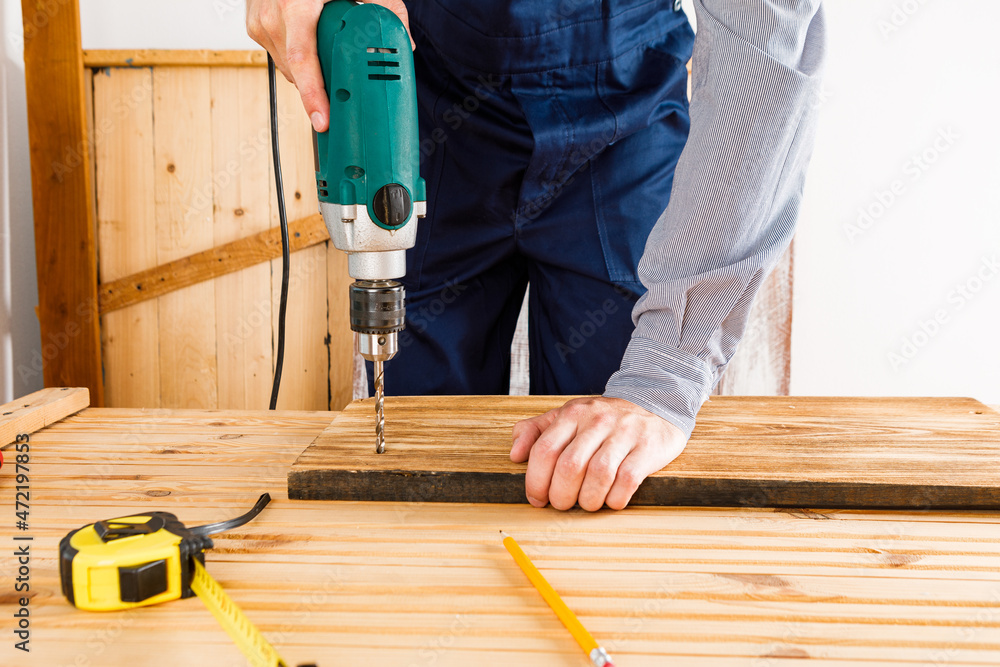 Handyman in blue uniform works with electricity automatic screwdriver. House renovation conception. Handyman in blue uniform works with electricity automatic screwdriver. House renovation conception.