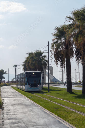Tram going Izmir Karsiyaka Turkey with background with trees and statue 