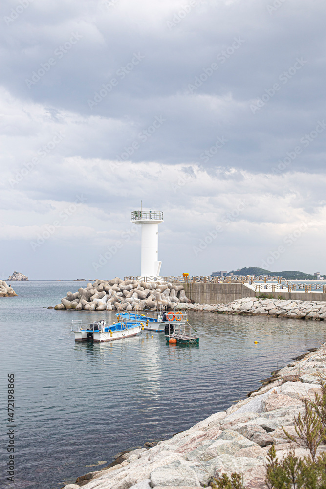 view of a lighthouse on breakwater against sea horizon.