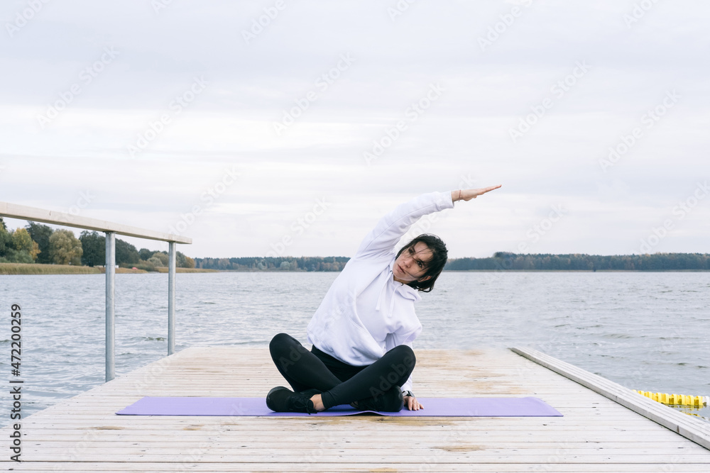 Portrait of a beautiful woman sitting on the mat, making yoga or stretching. Portrait of a beautiful woman sitting on the mat, making yoga or stretching.