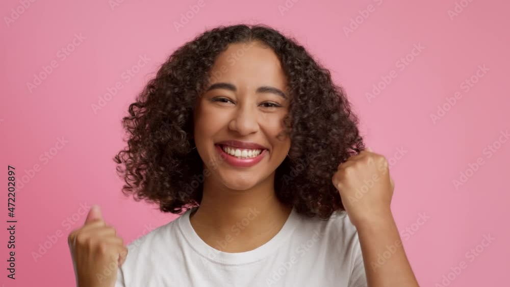 African American Female Shaking Fists Gesturing Yes Over Pink Background African American Female Shaking Fists Gesturing Yes Over Pink Background