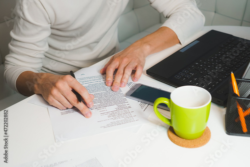 Man in white turtleneck hands working near notebook at home. Top view