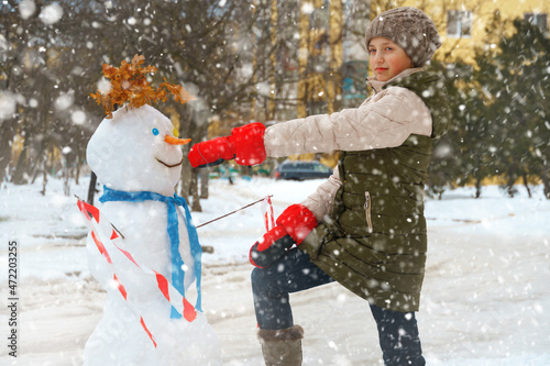 a girl plays with snow on a city street and makes a snowman
