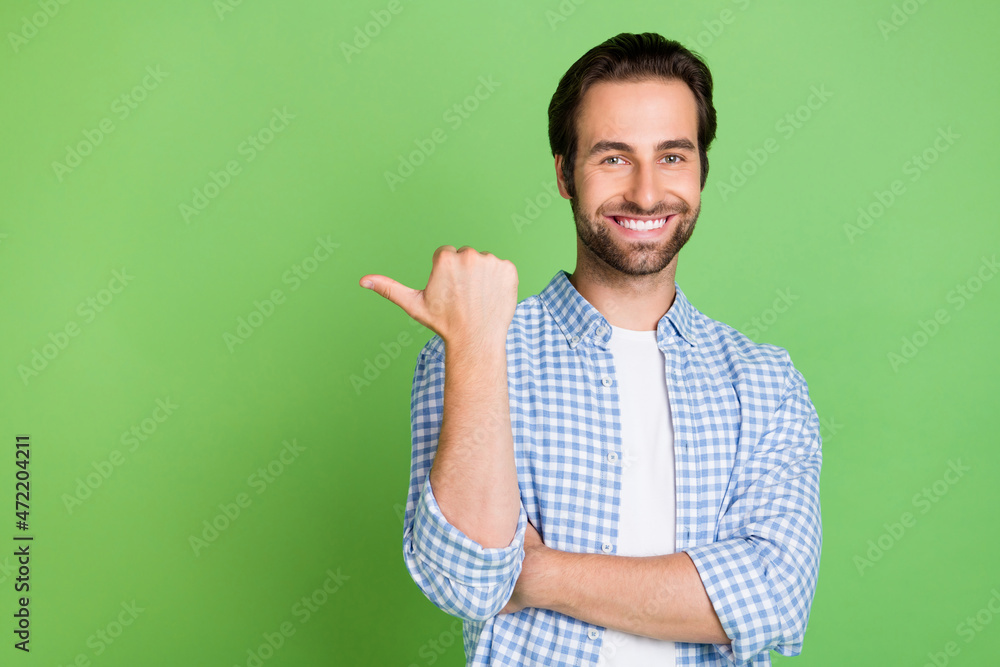 Photo of cute millennial guy indicate empty space wear checkered shirt isolated on green color background Photo of cute millennial guy indicate empty space wear checkered shirt isolated on green color background
