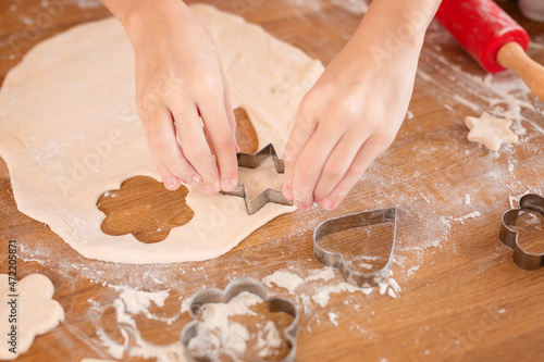 Sisters prepare holiday food for family together. Cute girls bake homemade festive biscuits. Lifestyle moment. A hand holding a piece of food. Children chef concept