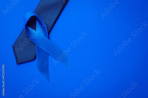 Cancer awareness blue. Blue ribbon, fashion tie isolated on deep blue background. Awareness prostate cancer of men health in November. November and International Mens Day.