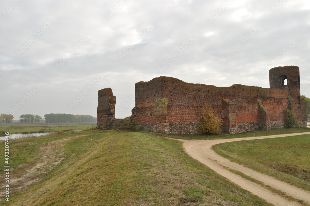 Castle ruins in Koło. Destroyed towers and defensive walls made of red brick on the bank of the Warta River.