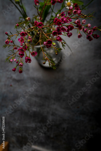 glass vase with red flowers stands on a gray table, top view