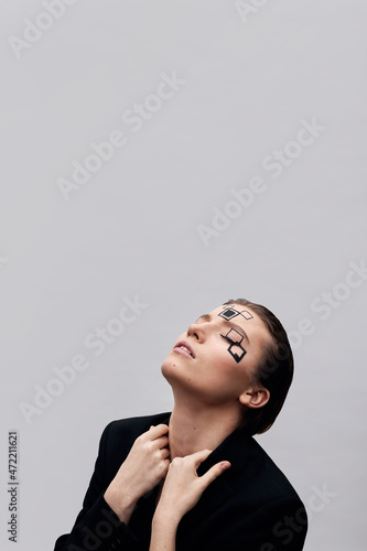 Fashion model with eyes closed touching lapels of jacket in front of white background photo