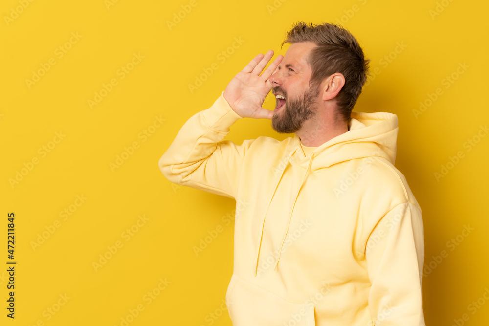 Young man over isolated yellow background shouting and screaming loud to side with hand on mouth. Communication concept. Young man over isolated yellow background shouting and screaming loud to side with hand on mouth. Communication concept.