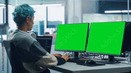 In Diverse Office: Female Programmer is Working on Green Screen Computer, Chroma key and Coding Language User Interface. Digital Entrepreneur Creating Software, e-Commerce App Design. Over Shoulder © Gorodenkoff