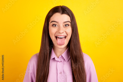 Photo of youth funky girl have fun show tongue rude childish humorous isolated over yellow color background