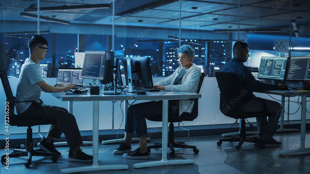 Diverse Office at Night: Multi-Ethnic Team of Young Programmers Working on Desktop Computers, Screens Show Coding Language User Interface. Software Engineers Create Innovative e-Commerce App. Diverse Office at Night: Multi-Ethnic Team of Young Programmers Working on Desktop Computers, Screens Show Coding Language User Interface. Software Engineers Create Innovative e-Commerce App.