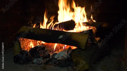 Burning firewood in fire-box of fireplace. A brick fireplace in which a fire is burning.
