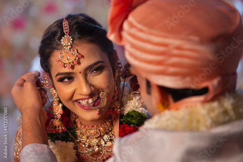 Indian groom tying mangal sutra around bride neck wedding ceremony photo