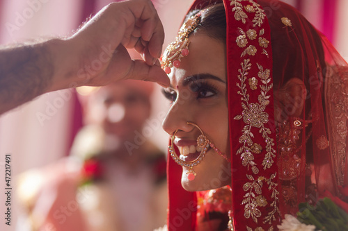 Indian groom putting sindoor on brides forehead during wedding ceremony photo