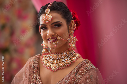 Portrait of beautiful smiling Indian bride in traditional wedding clothing and jewellery photo