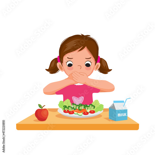 Cute picky eater little girl unhappy covering her mouth refusing to eat vegetables. photo