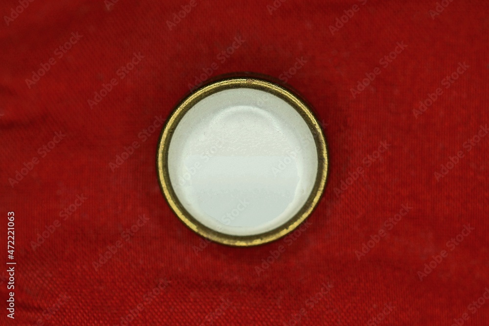 one large white plastic button on red clothing fabric one large white plastic button on red clothing fabric