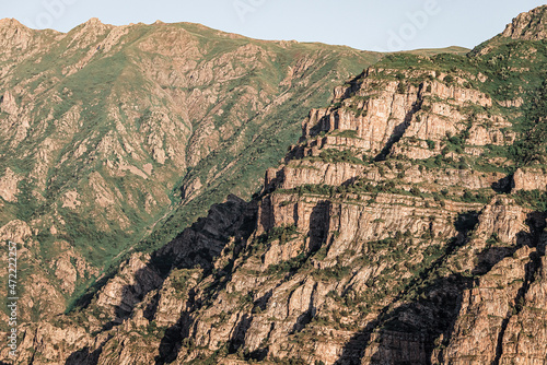 Cliff and rocks of the mountains create an amazing pattern illuminated by the rays of the setting sun. The play of light and shadow photo