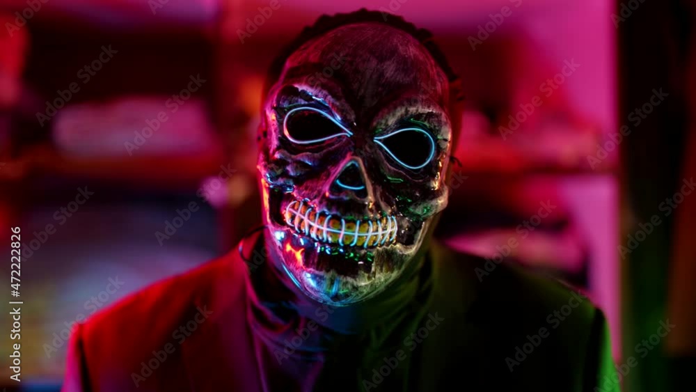 gloomy man with face mask of scaring skull in nightclub in Halloween night gloomy man with face mask of scaring skull in nightclub in Halloween night