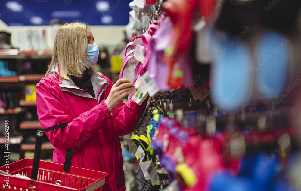 Naklejka premium Woman in medical mask is choosing flip-flops.
