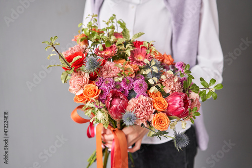 Beautiful large bouquet of mixed flowers without packaging. Handsome fresh bouquet in woman hand. Small flower shop and Flowers delivery.