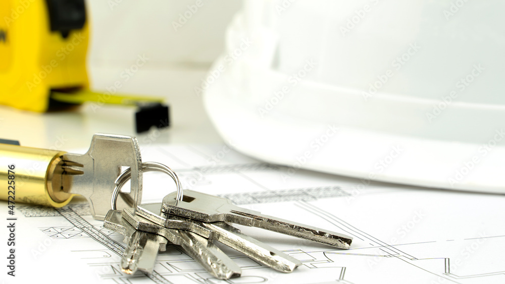 helmet and keys to the house and the layout of the house on the drawings. the concept of construction and purchase of new housing