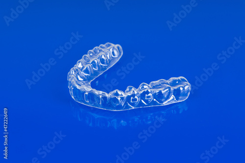 Invisible orthodontics cosmetic brackets on blue background. Tooth aligners, for beautiful smile.