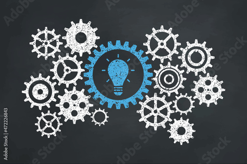 The business gear concept on the blackboard. Blue light bulb icon