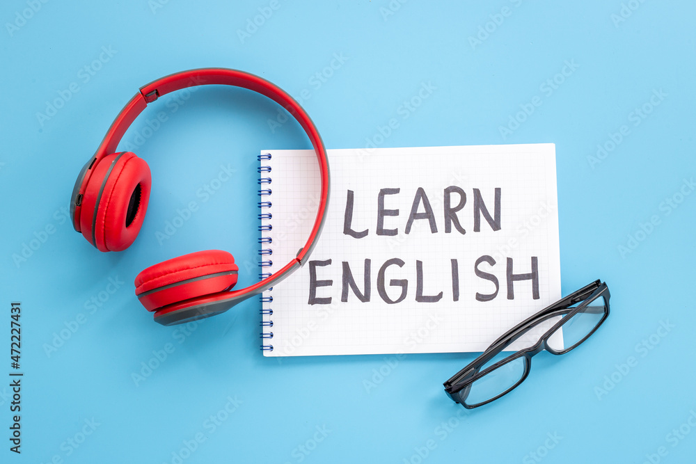 English lessons concept. Headpones with notebook on student table desk English lessons concept. Headpones with notebook on student table desk