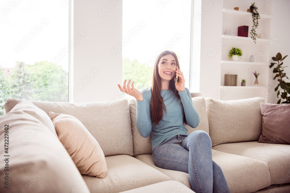 Photo of young attractive girl happy positive smile sit sofa speak talk cellphone conversation listen home Photo of young attractive girl happy positive smile sit sofa speak talk cellphone conversation listen home