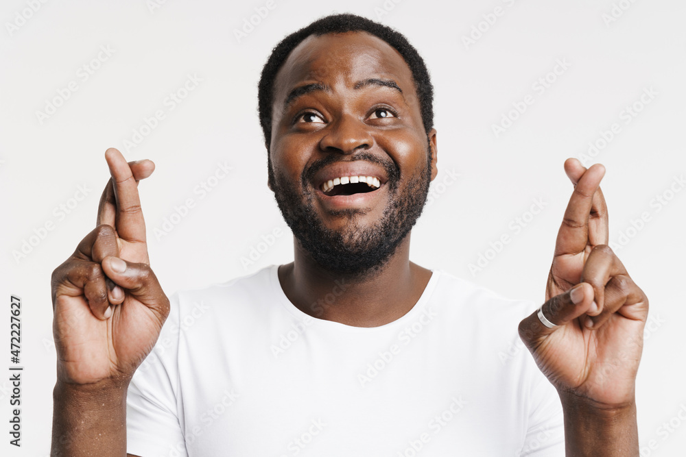 Black bristle man smiling while holding fingers crossed for good luck Black bristle man smiling while holding fingers crossed for good luck