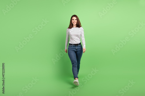 Full size photo of young attractive woman good mood go walk wear casual clothes isolated over green color background
