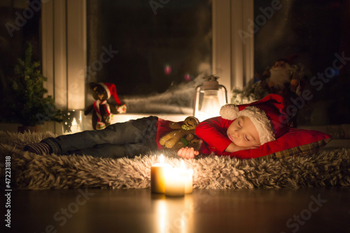 Beautiful toddler child, boy, sleeping on Christmas eve, waiting for Santa Claus to come