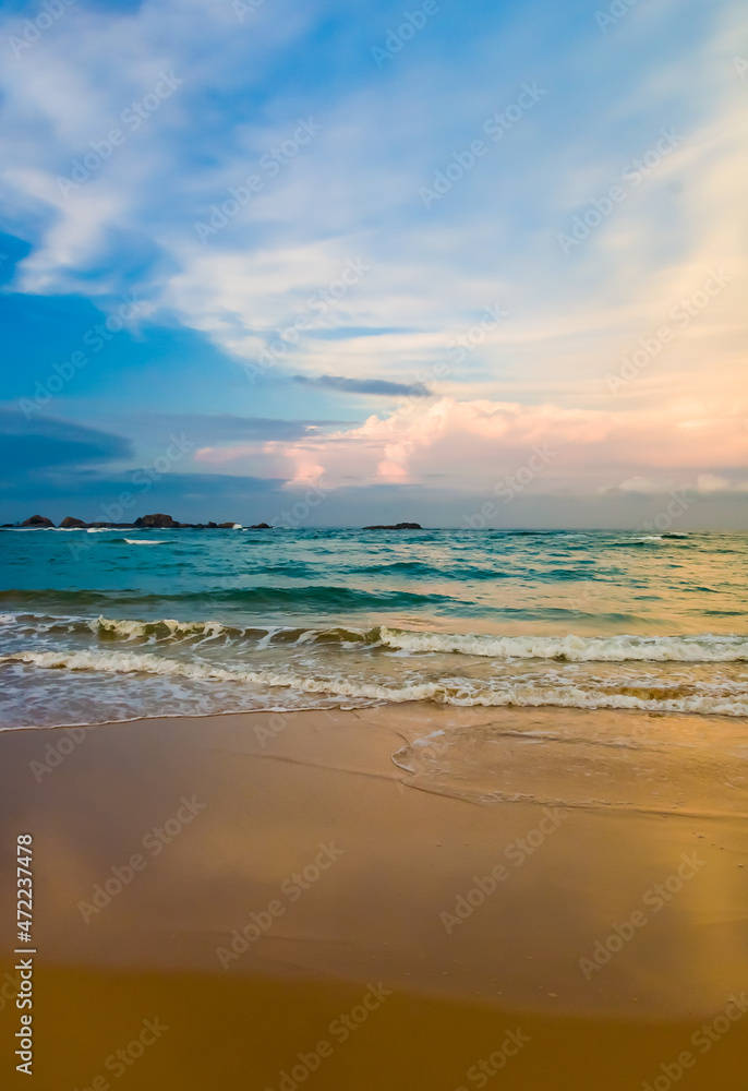 Landscape with a sandy seashore against the sky with clouds in the city of Hikkaduwa in Sri Lanka