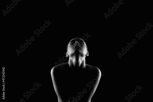Nude Woman silhouette under light in the dark
