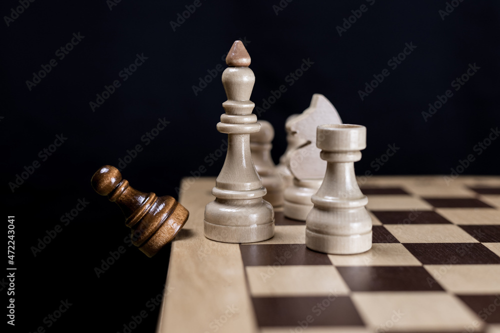 The white chess king and his team consisting of a rook, knight and pawn discards the opponent's black pawn from the chessboard. Concept of White's victory in chess, victory over the opponent, teamwork The white chess king and his team consisting of a rook, knight and pawn discards the opponent's black pawn from the chessboard. Concept of White's victory in chess, victory over the opponent, teamwork