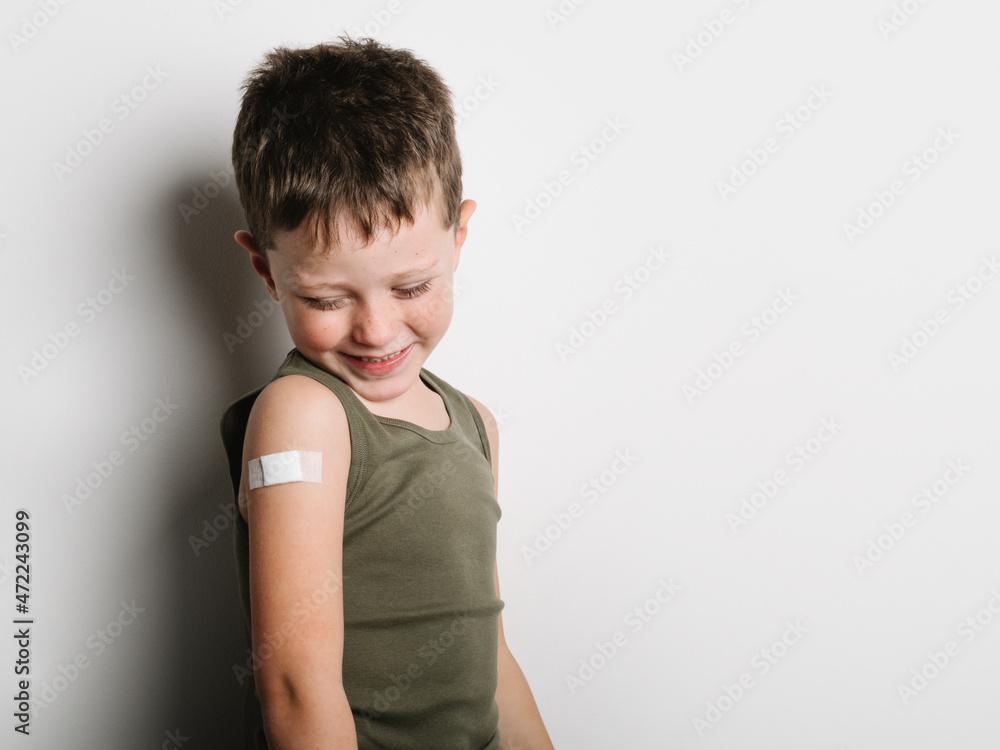 Cheerful schoolboy after vaccination with band aid on arm Cheerful schoolboy after vaccination with band aid on arm