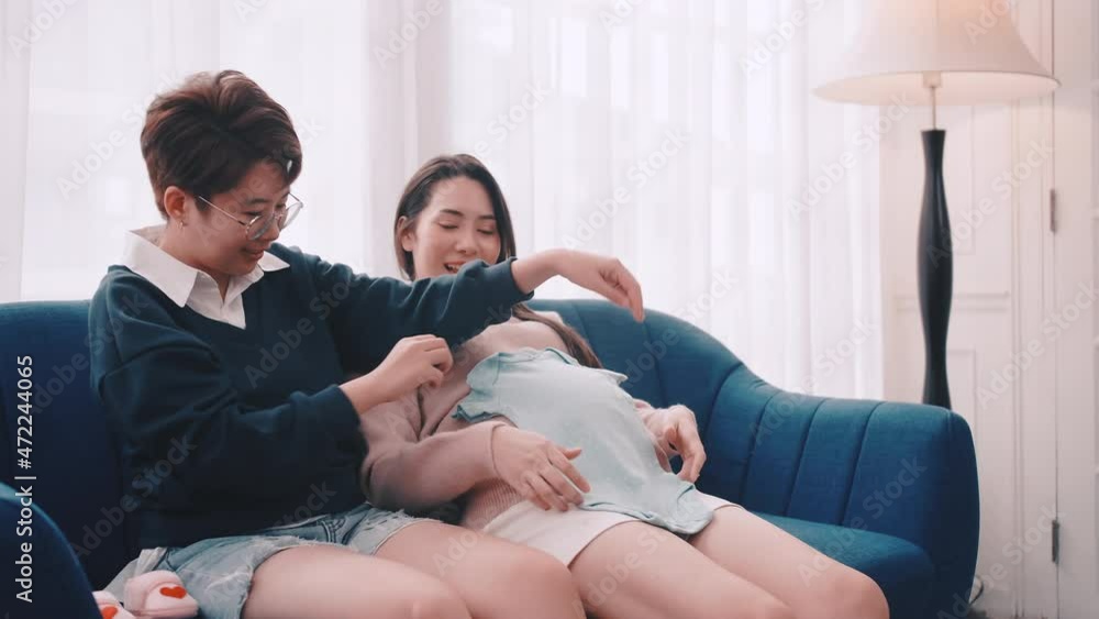 Pregnant Asian lesbian woman and her partner are happy to spend time together at home. Pregnant Asian lesbian woman and her partner are happy to spend time together at home.