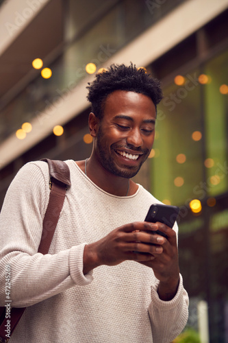 Male Vlogger Or Social Influencer In City Using Mobile Phone On Street To Post To Social Media photo