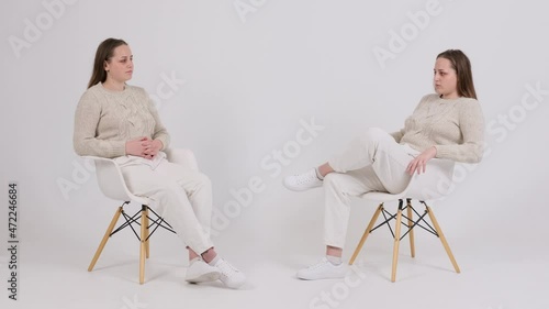 Woman talking with her clone on white background photo