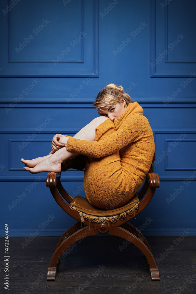 Young woman curled up in an old armchair