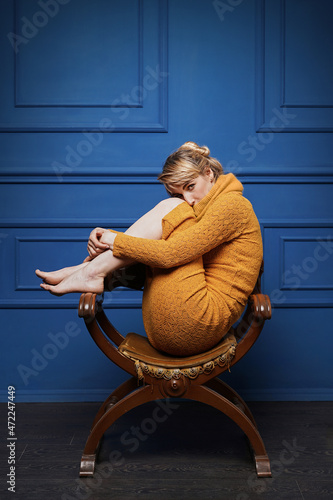 Obraz na płótnie Young woman curled up in an old armchair w salonie