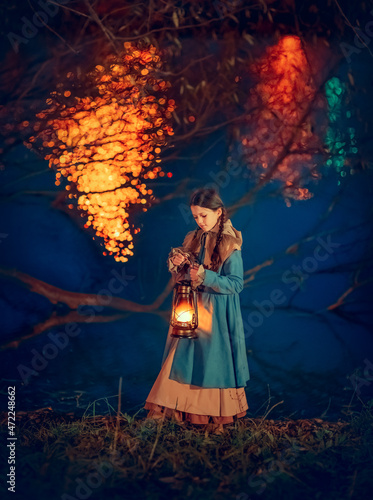 Girl with lantern near lake in the night autumn park