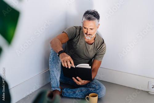 Old male in corner enjoying book reading photo